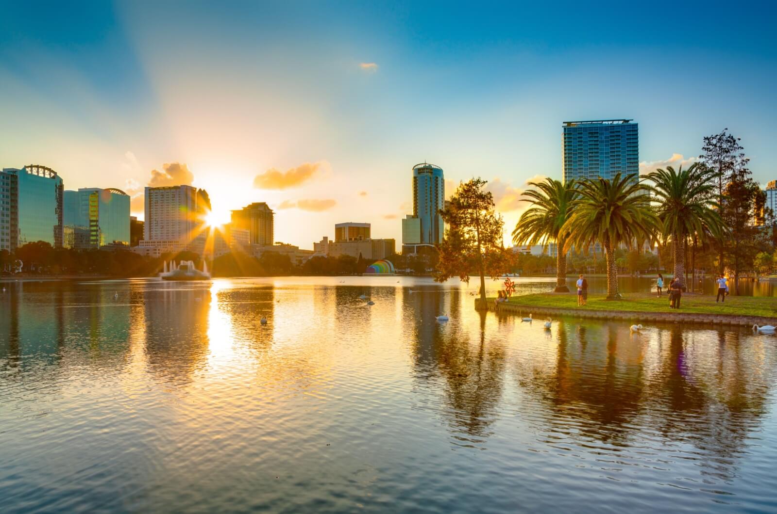 An aerial view of a lake beside Orlando, Florida, with the sun setting in the background.