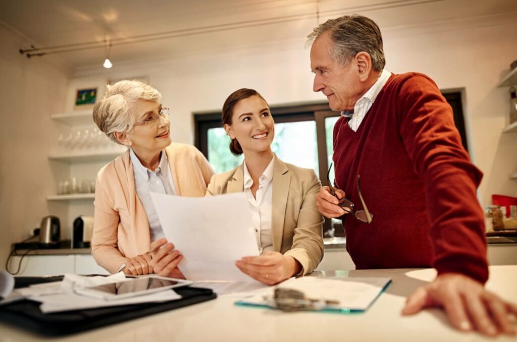 A professional-looking woman explains important legal paperwork to two seniors.