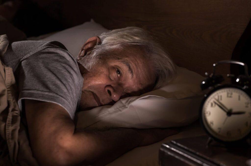 A senior man struggling with depression lying on his bed, dealing with a reduced appetite.