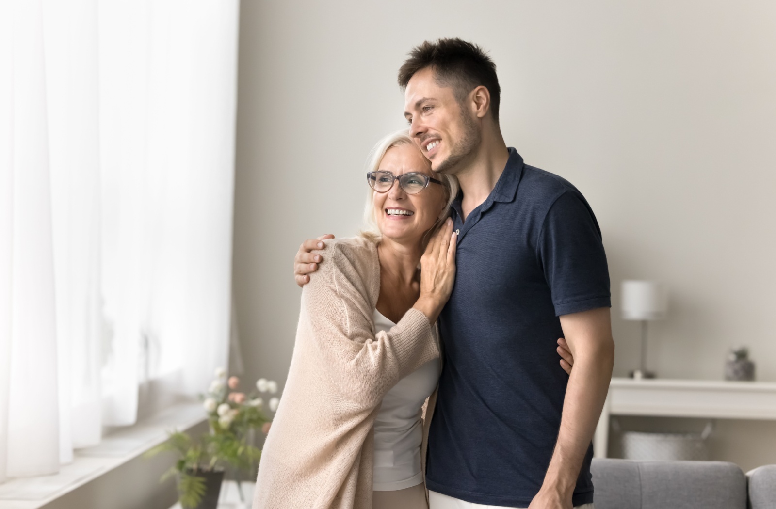 An older adult and their adult child hugging from the side as they plan a move into assisted living