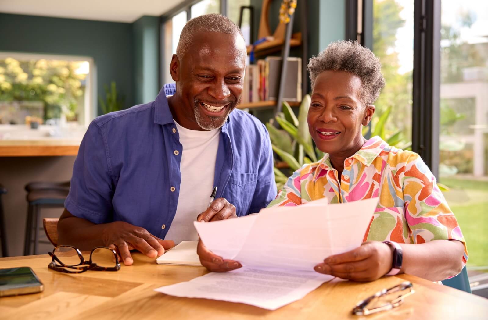 An older couple sitting at a table and looking at papers to go over their financial plan for assisted living