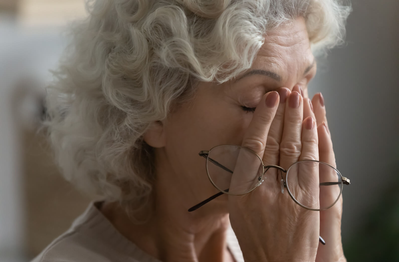 An older adult with dementia yawning and rubbing their eyes in the middle of the day.