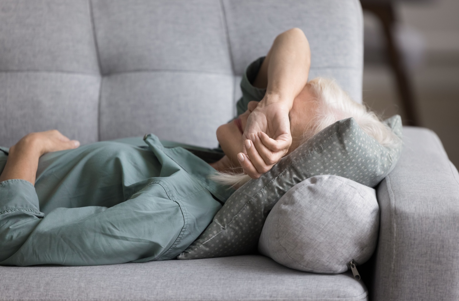 An older adult with dementia lying on the couch in the middle of the day to take a nap.